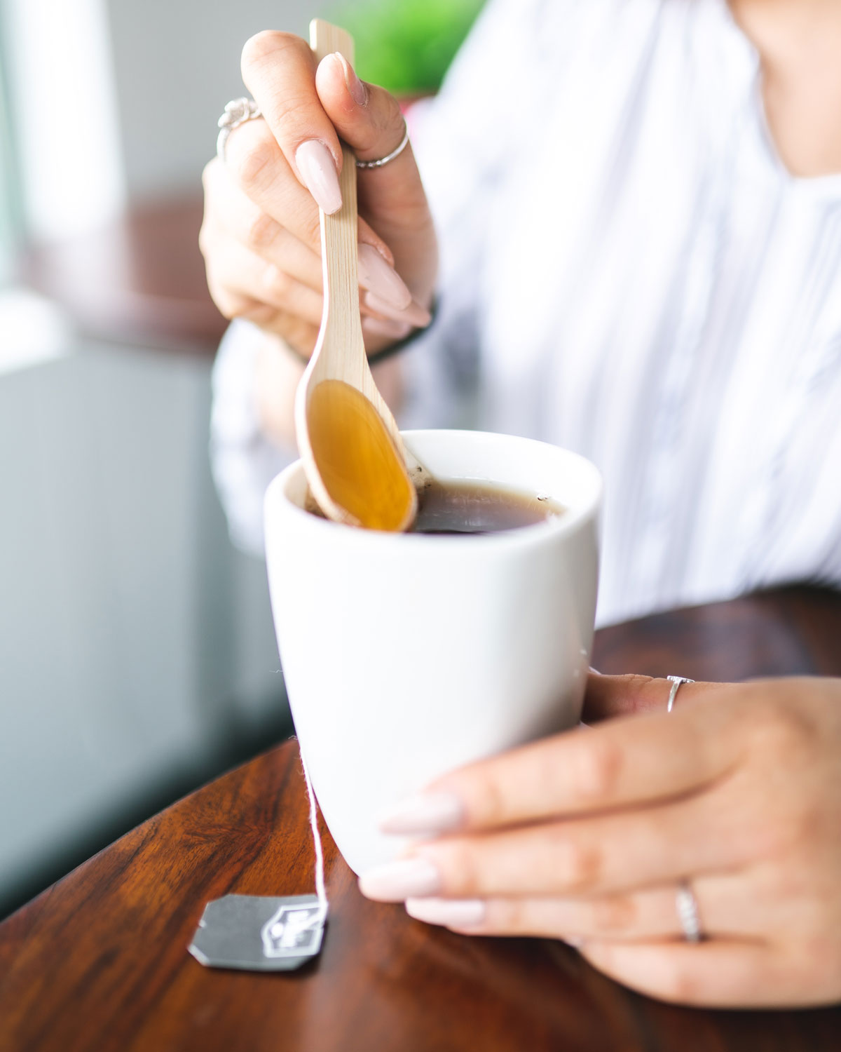 Reusable bamboo spoon stirring a cup of hot tea